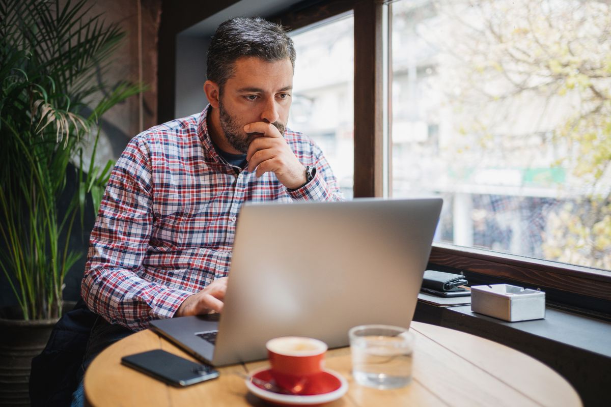 Small business owner working on a laptop in a café, reviewing digital tax records for Making Tax Digital compliance in 2025