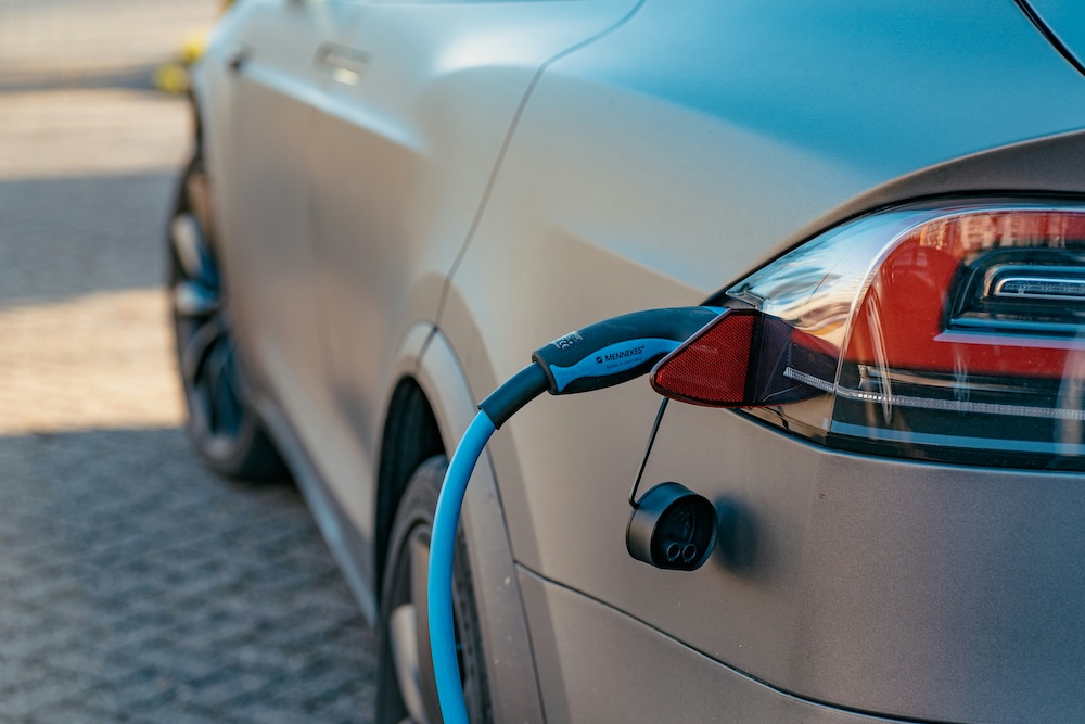 Close-up of an electric vehicle charging in an outdoor parking area, illustrating growing adoption of EVs supported by UK electric car tax benefits 2025 aimed at promoting cleaner transportation.